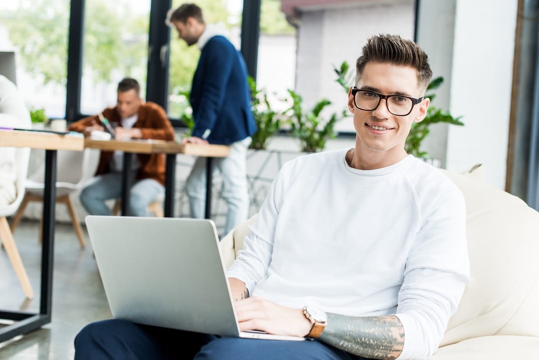 615b674203e390f83edb0a3e crello 309540420 stock photo young businessman using laptop smiling p 1080