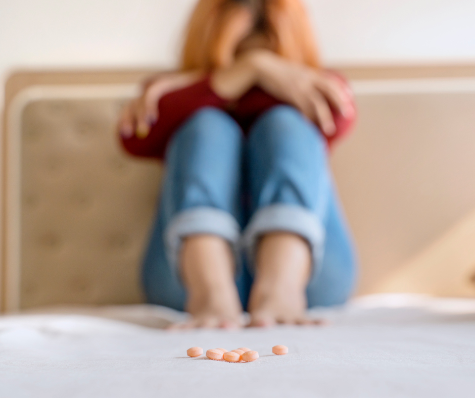 A young woman with her heads in hands knowing that pills are getting the best of her. 